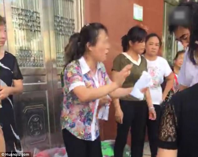 The woman's family member (middle) explained how she had died to onlookers outside her ex-husband's home in eastern China. The woman had been forced to go through four abortions.