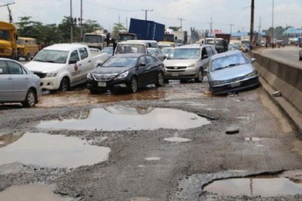 Nigerian Youths Dig Hole In The Road So Motorists Can Pay For Their Plank To Be Used As Bridge