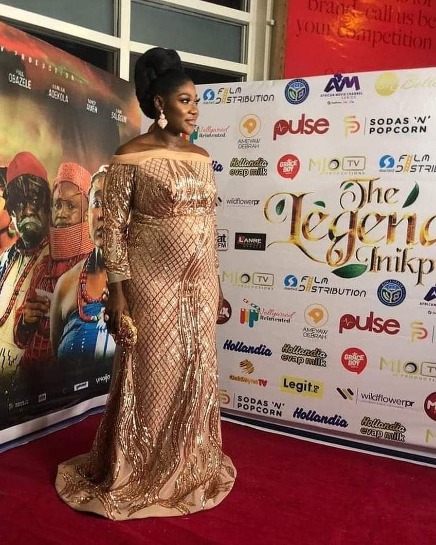 Mercy Johnson cradles her growing baby bump as she steps out for the premiere of her first directorial movie