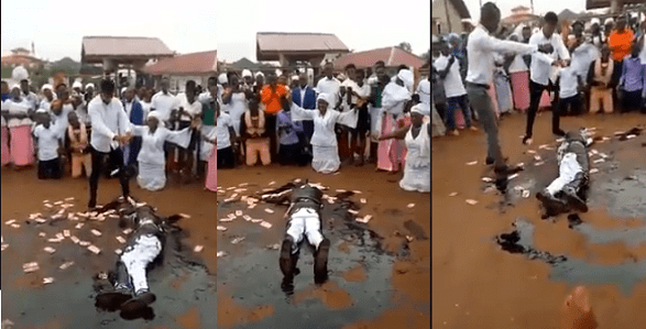 Pastor stirs controversy as he rolls in engine oil, while members spray money on him during church crusade (Video)